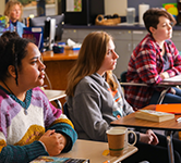 Three students sitting at desks in a classroom