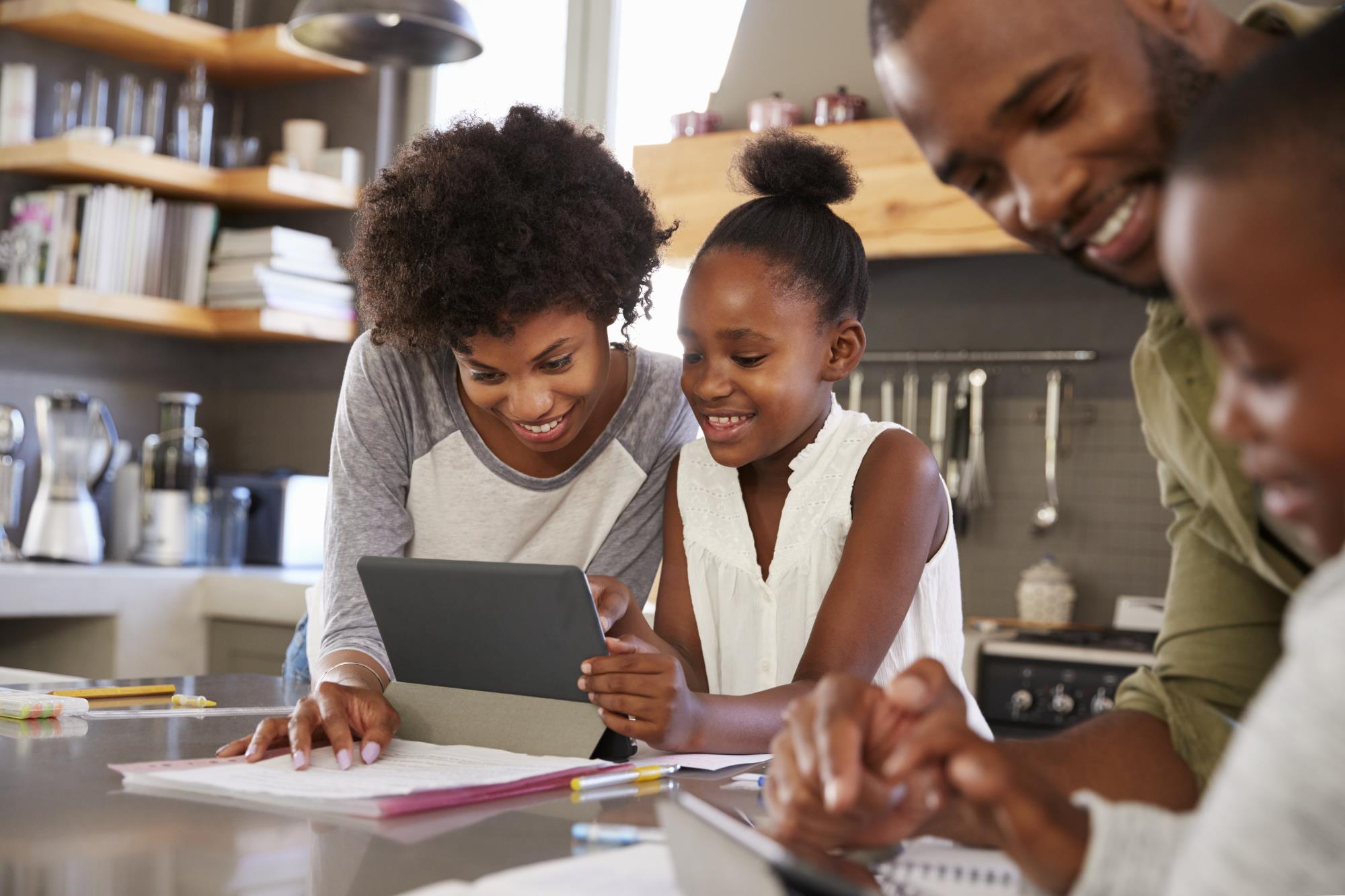 Mom and dad do schoolwork with children in kitchen