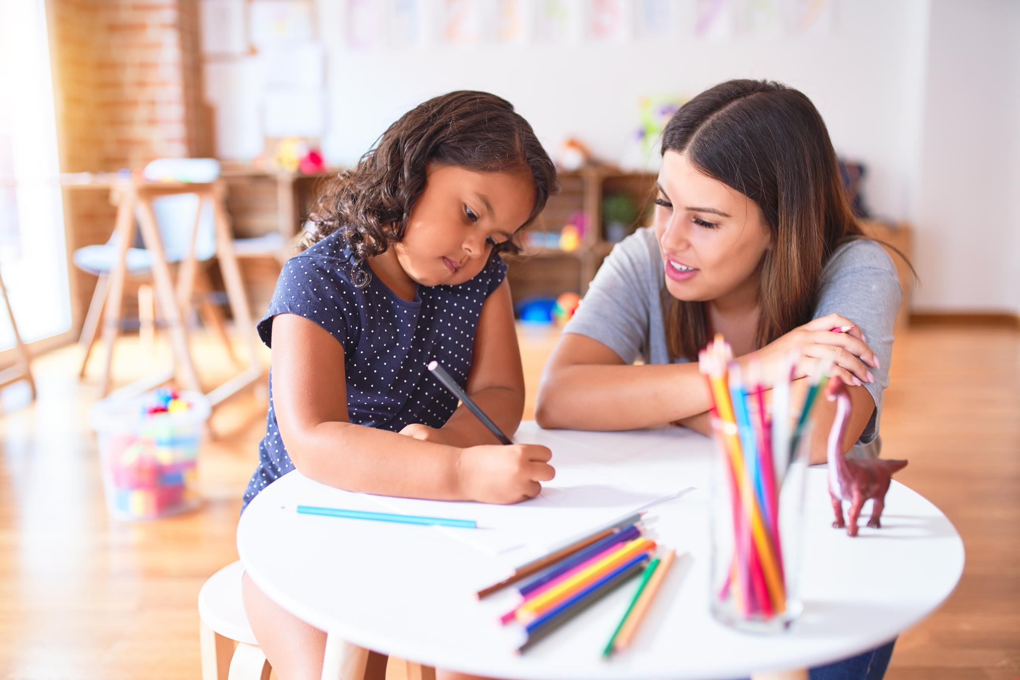 teacher works with an elementary aged student as she colors