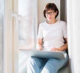 woman sitting in front of a laptop in a window