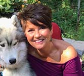 A white woman with short brown hair poses with her dog