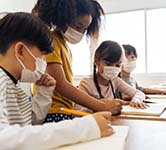 students in masks work on a school project