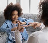 child sitting on a couch signing to a woman