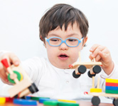 preschool boy wearing blue glasses plays with blocks