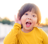 young girl holds her hand up to her ear