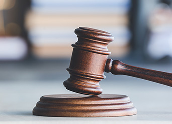 Wooden gavel with papers in the background