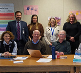 board members, licensed staff and superintendent pose in a conference room