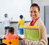 teacher holds folders while students work at a whiteboard