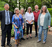 foundation board members stand outside with trees in the background