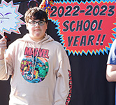 middle school student holds up a white sign with a 2022-23 school year sign