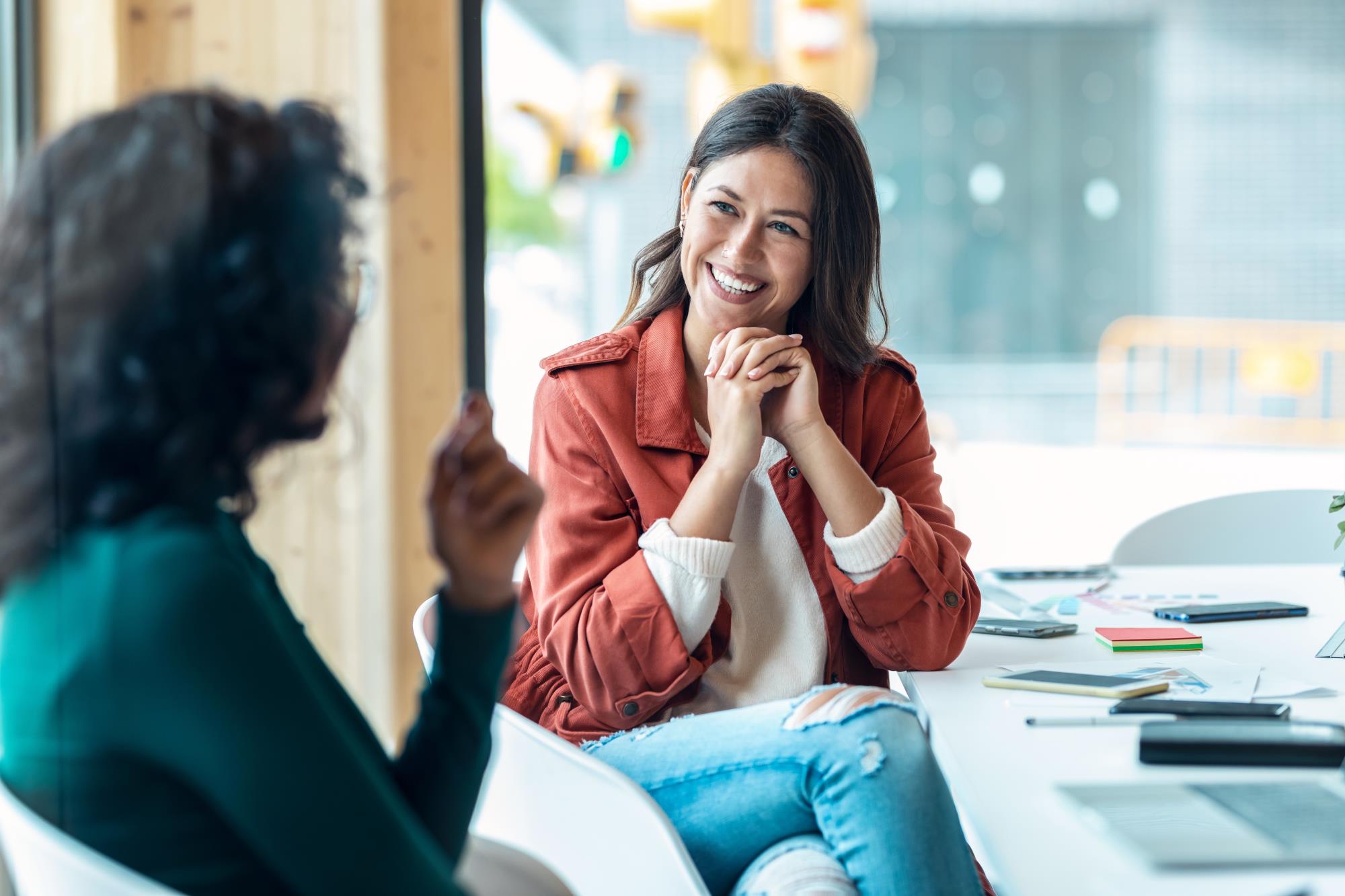 Two women sit at a table in a conference room