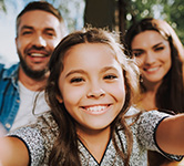 elementary aged girl holds up a camera to herself and her parents