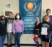 teacher and students pose with a blue poster that says america's healthiest schools