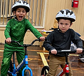 two preschoolers pose for a photo on their balance bikes