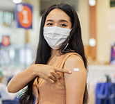 woman points to a Band-Aid on her arm