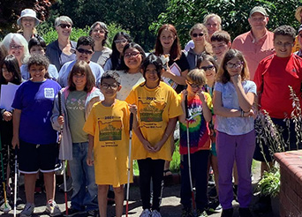 students and teachers pose for a photo outside with trees in the background