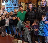 rebecca clifton poses with children and the adults who help her run her child care business