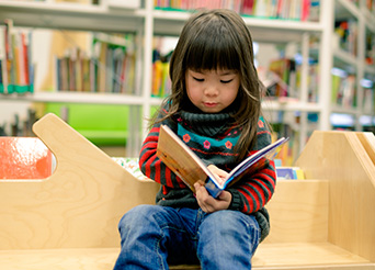 young girl reading a book at the library