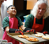 riley lifts pizza from oven with help from sue