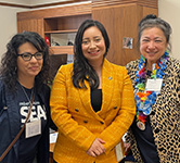 three women stand together in an office