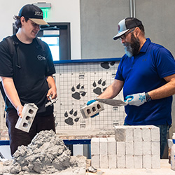 a bricklayer works with a student during a career fair