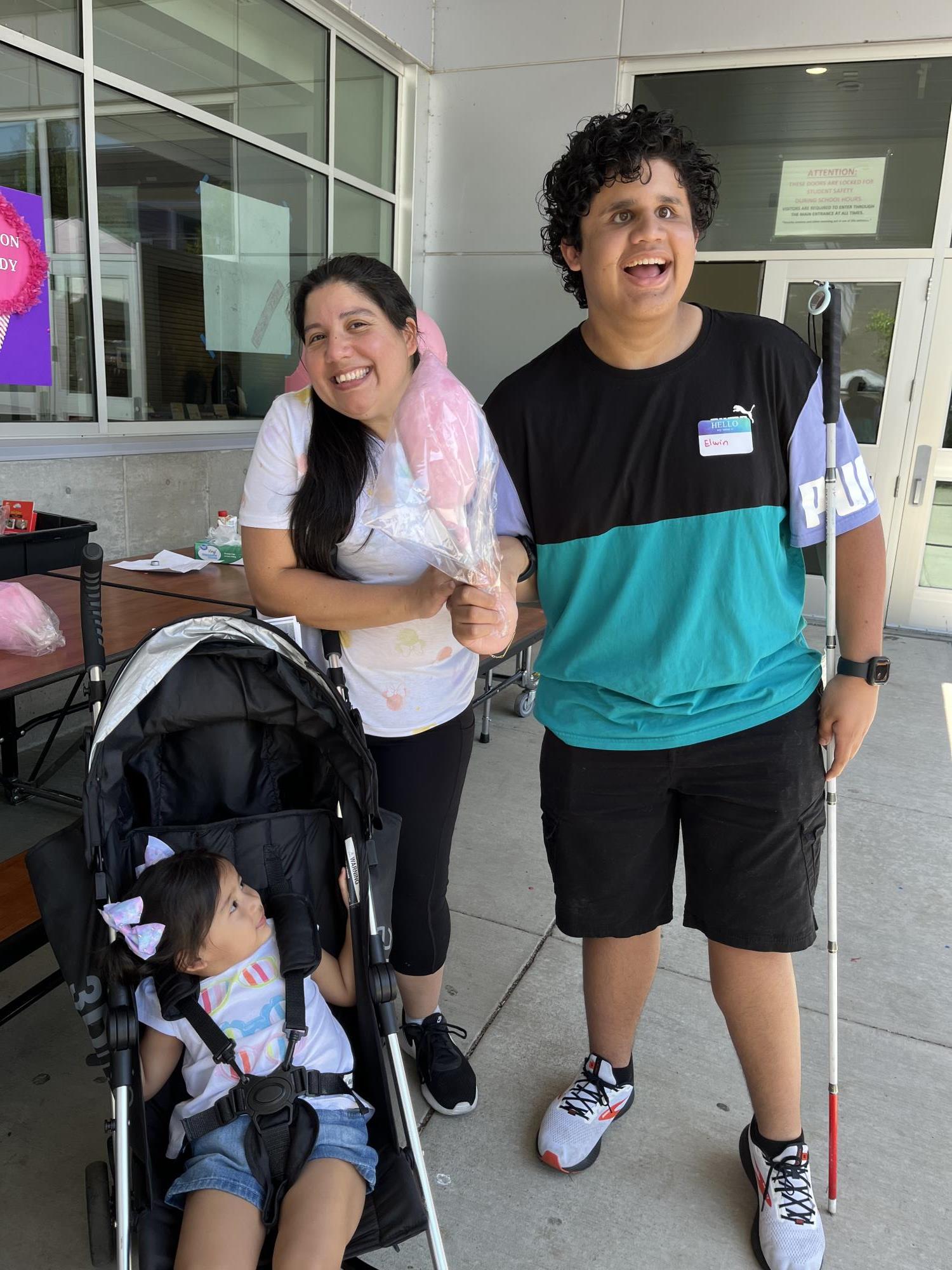 Elwin holds cotton candy as he poses with a photo with his mom and sister