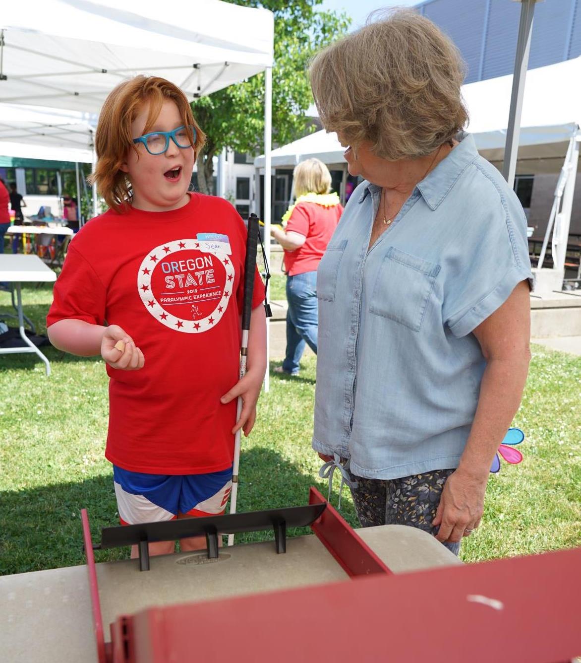 Sean plays adaptive Skee-Ball under an outdoor tent