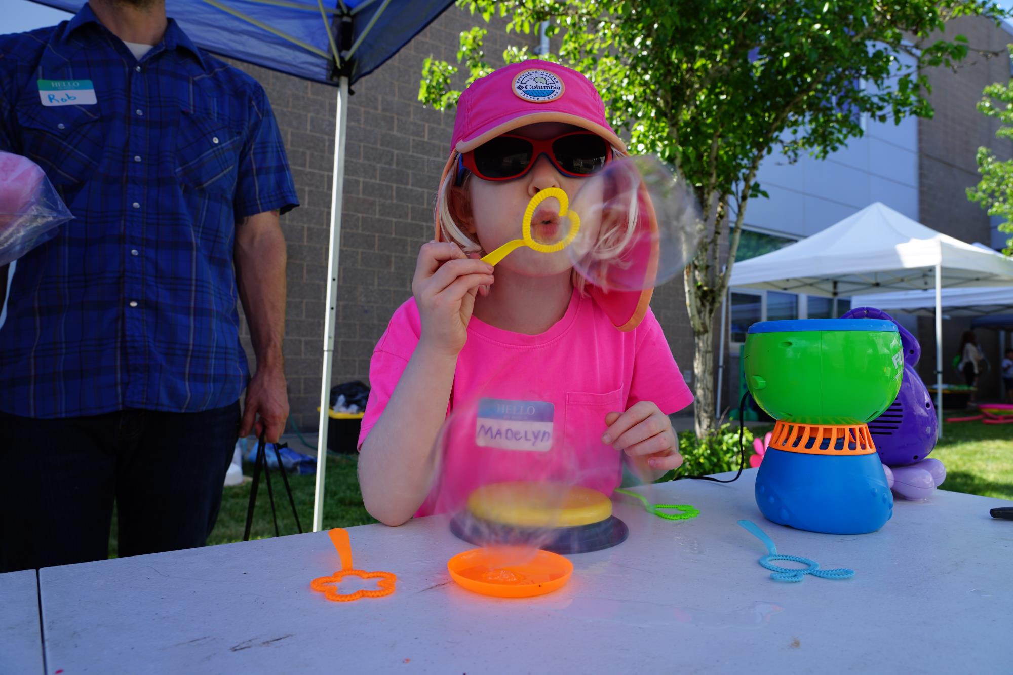 Madelyn wears a hot pink t-shirt and hat and blows a bubble