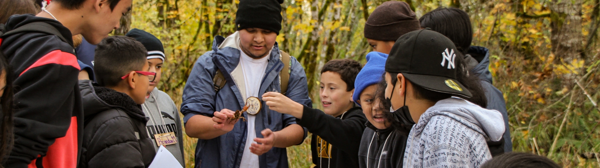 Group of students gather to look at creature with older student