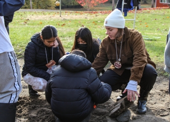 Group of four people crouching and sitting looking at the ground