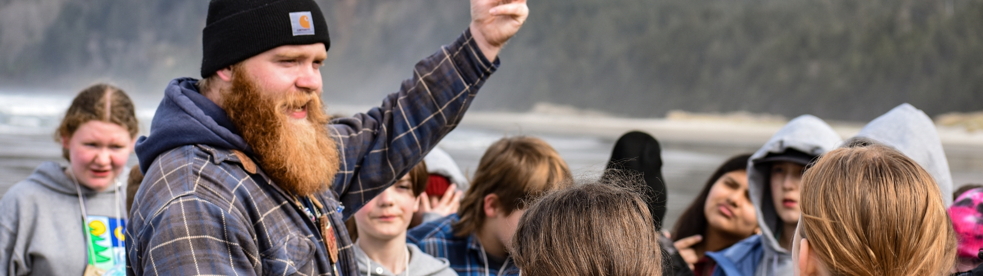 Person talking to group of kids on beach with ocean in the background