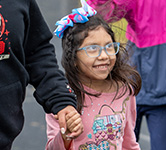 student with vision impairment holds an educator's hand as she races