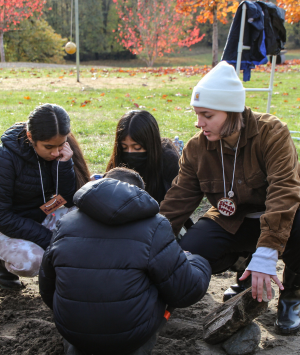 Group of students sitting on the ground outside observing something