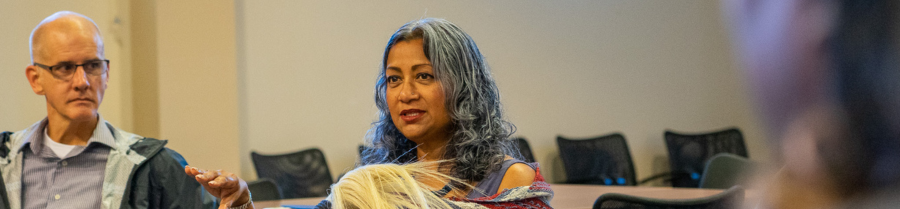 Close up of a woman with gray hair talking and a man with glasses looking at her