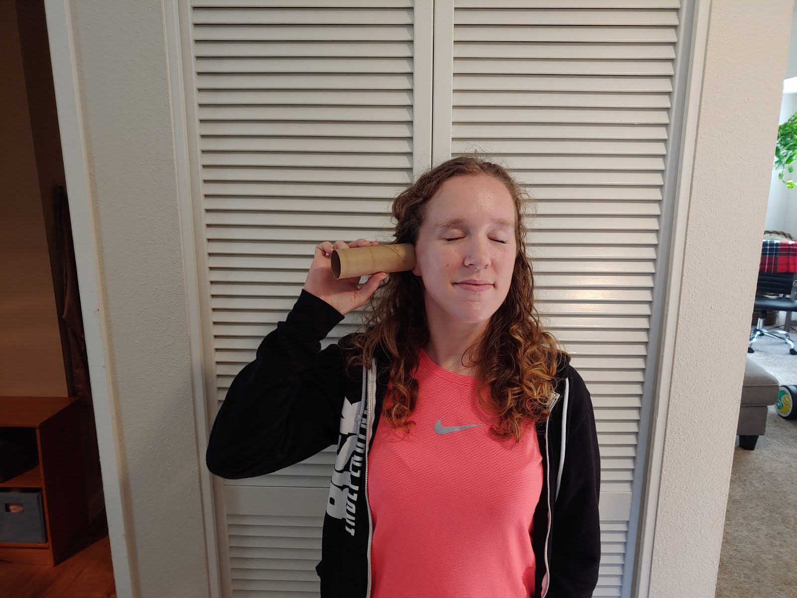 a picture of a person listening with a toilet paper roll pressed against their ear, and with their eyes closed