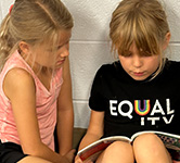 two elementary students read a book together