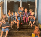 young children sit on the front steps of a house