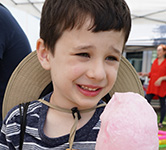 an elementary-aged student holds pink cotton candy outside