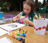 Student in a tie dye shirt draws a cat