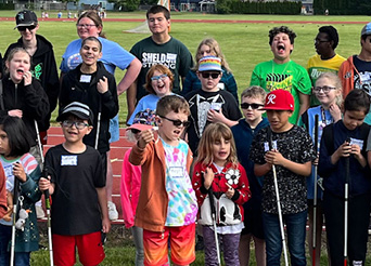 students who are blind or visually impaired pose for a photo next to a track