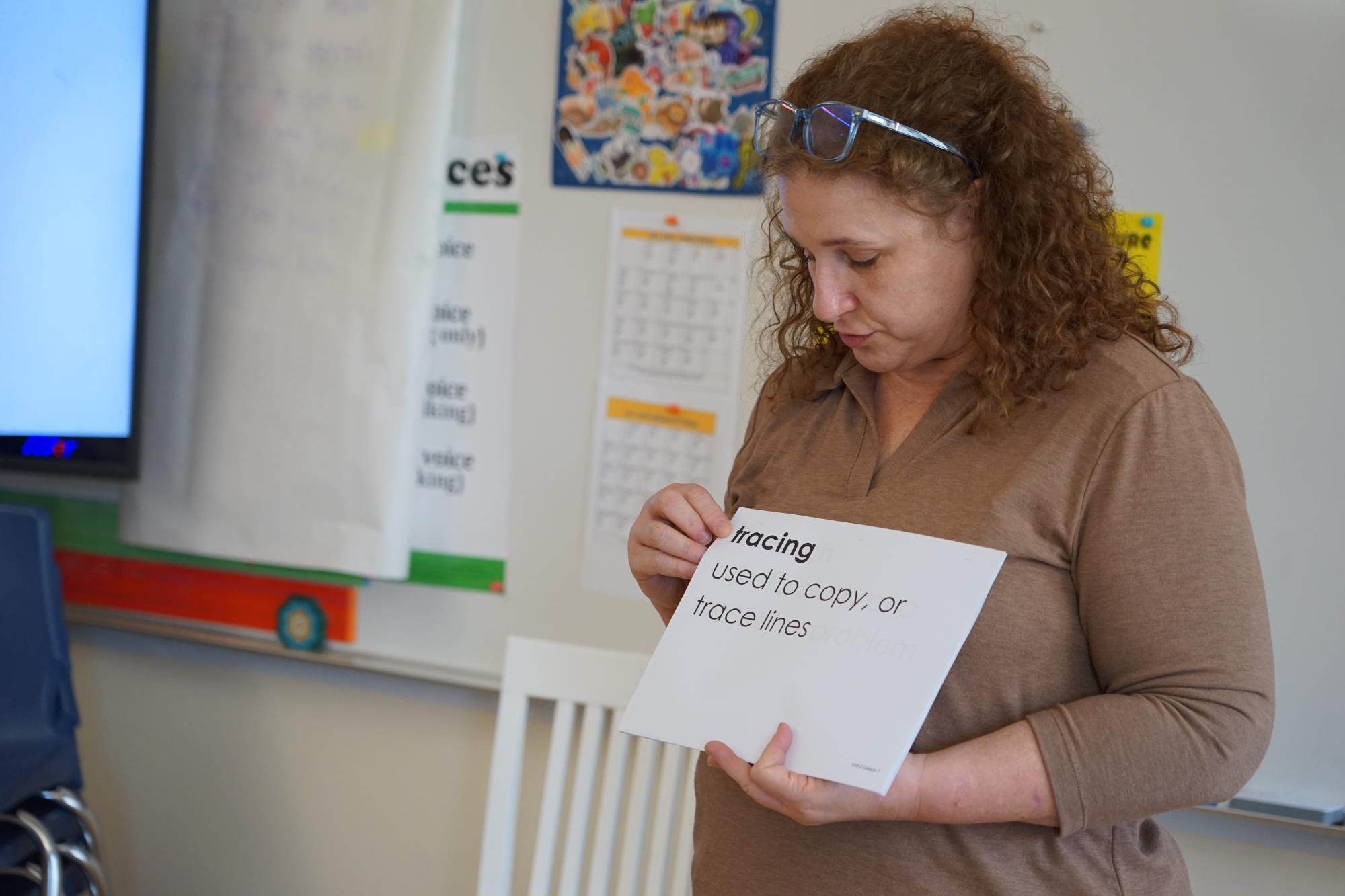 Heidi Rice holds up a card that says tracing and has students practice the word