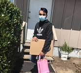 Eddy Sanchez in a mask, holding packages